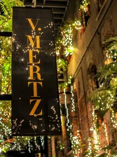 sparkly lights and greenery by V Mertz sign outside restaurant