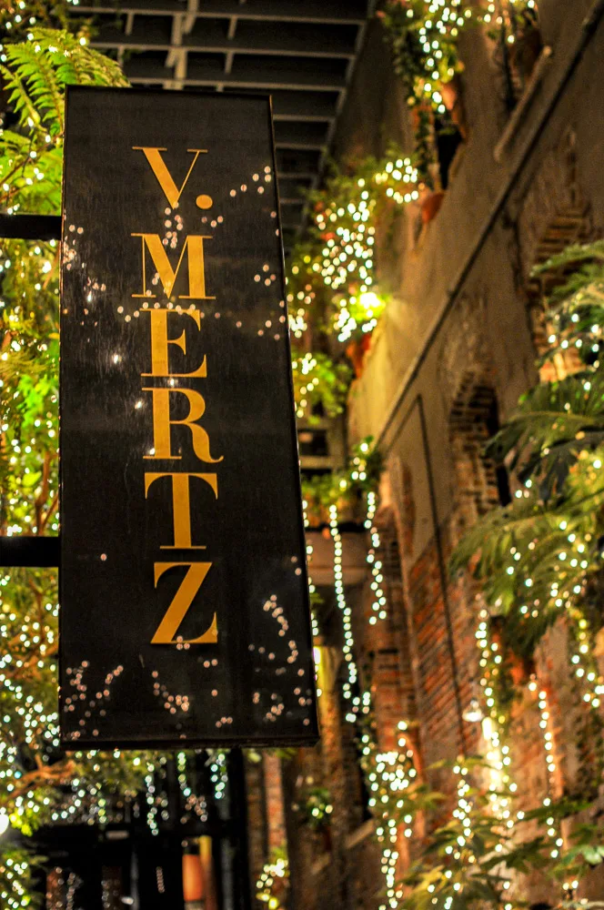 sparkly lights and greenery by V Mertz sign outside restaurant