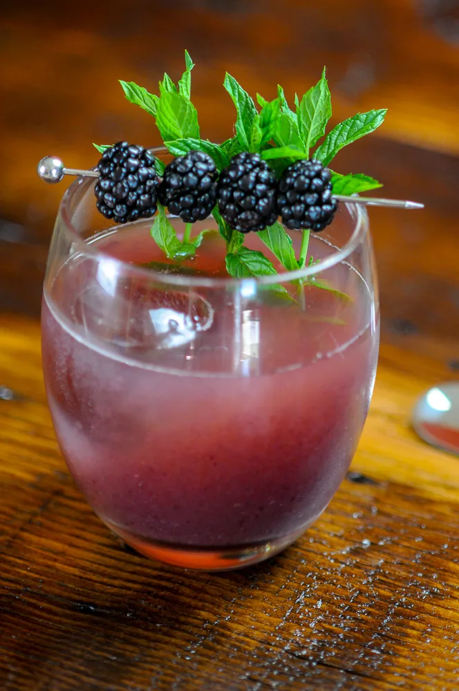 Honey Blackberry Whiskey Shrub Cocktail with clear ice. Blackberries and mint garnish.