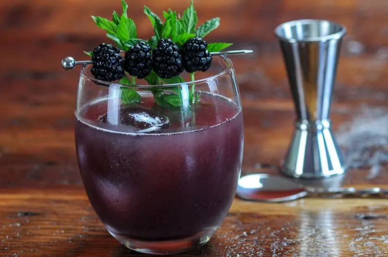 Honey Blackberry Shrub Whiskey Cocktail in a glass with clear ice, mint and blackberries