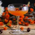 Manhtaan cocktail in a coupe, fall flowers behind