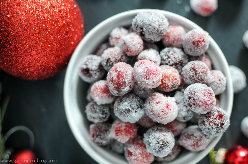 Sugared Cranberries in a white bowl, ornaments in back