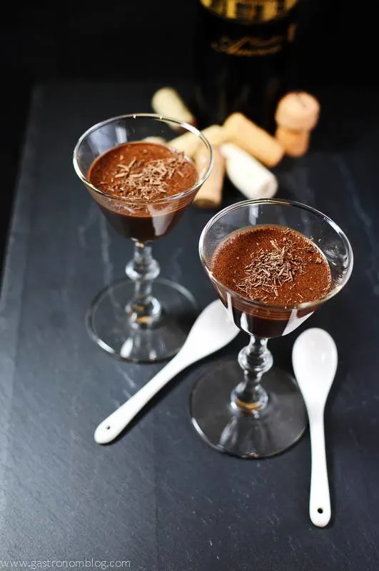 Chocolate pot de creme dessert in glasses with white ceramic spoons and corks and wine bottle in background