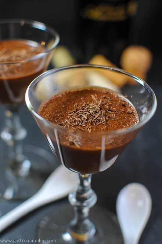 chocolate dessert in glass with white ceramic spoons and wine corks in background