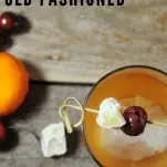 Top shot of a whiskey cocktail in a rocks glass with ginger and cherries