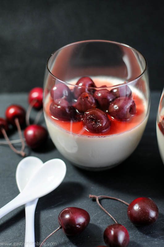 Old Fashioned Panna Cotta in a glass with brandied cherries, white spoons and cherries