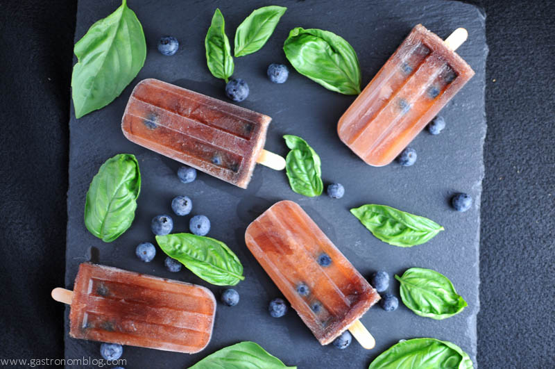 Red wine Icepops with basil leaves and blueberries on a slate