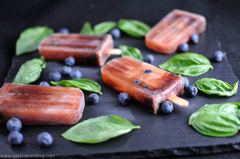 Red wine icepops with basil leaves and blueberries on slate