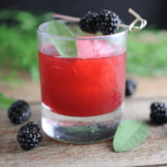 red blackberry sage cocktail in rocks glass with berries and sage leaves