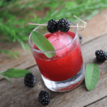 Red cocktail with sage leaves and blackberries