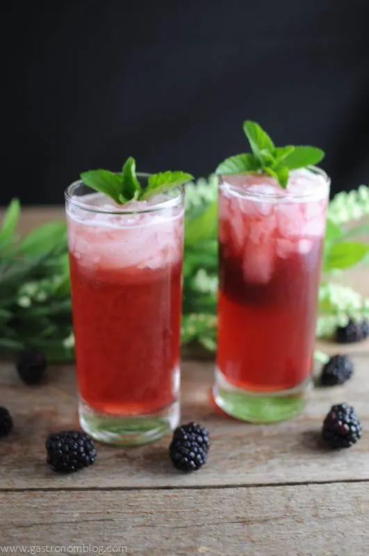 St Pisco Smash cocktails in two highballs with flowers and blackberries in background