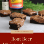 Root Beer Whiskey Brownies on parchment, whiskey bottle, bitters bottle and greenery in background