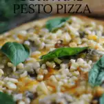 Corn and Basil Pizza on cutting board with basil leaves and cob of corn