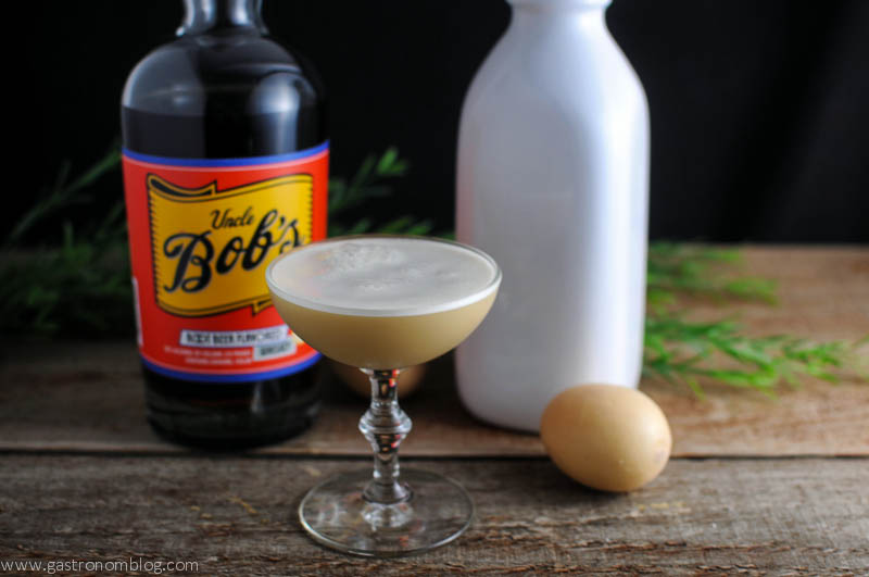 Root Beer Whiskey Flip Cocktail in a coupe, bottle behind