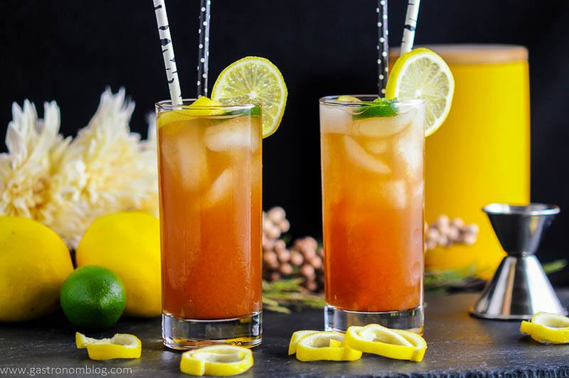 Two tall glasses of Tomato Water Bloody Mary Cocktails made with vodka, lemon juice and hot sauce, garnished with lemon and lime curls.