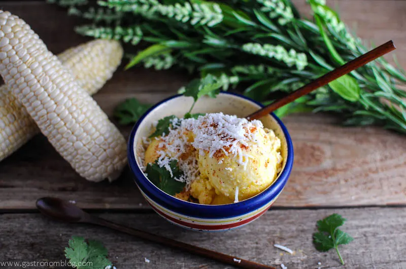 Corn Ice Cream in striped bowl with corn ears and flowers in the background