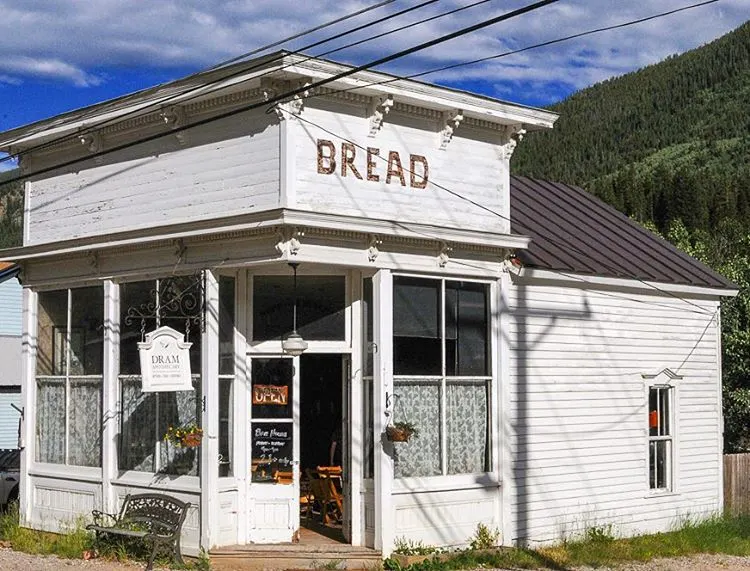 White building with bread written on side, blue sky and mountain in background