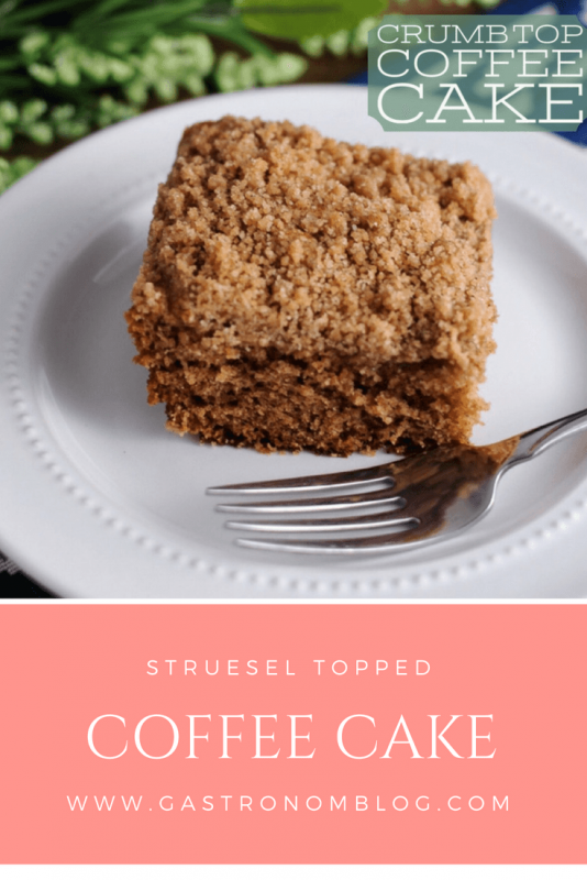Streusel Topped Coffee Cake for breakfast or brunch with fork on white plate. Greenery behind