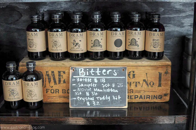 Bitters bottles lined up and on top of wooden box, with chalkboard sign saying bitters