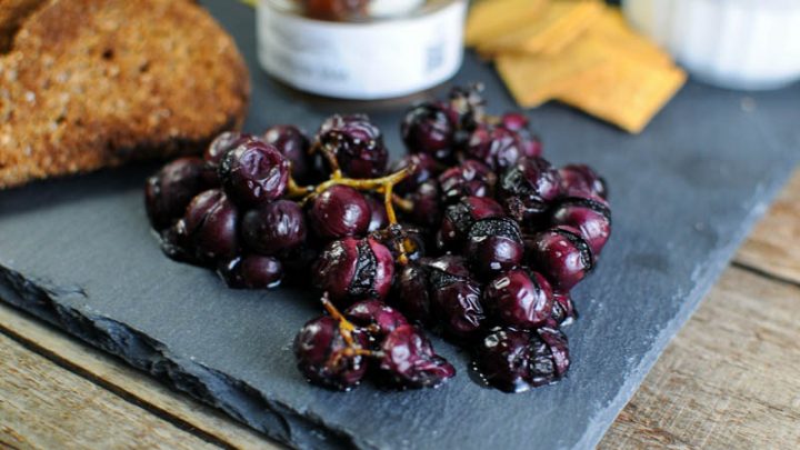 Grapes on slate with jam jar, toast and crackers behind