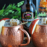 Copper mugs with cocktails, vodka bottle and ginger beer bottle behind