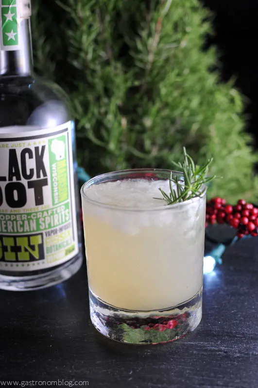 Rosemary's Pear cocktail, greenery and gin bottle in background