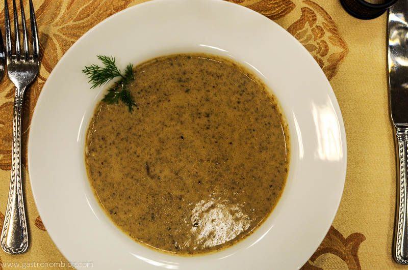 White bowl of mushroom soup, parsley garnish, on an autumn napkin. 