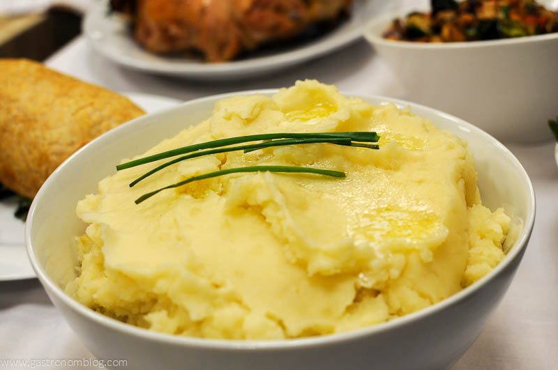 Mashed potatoes in white bowl, topped with chives