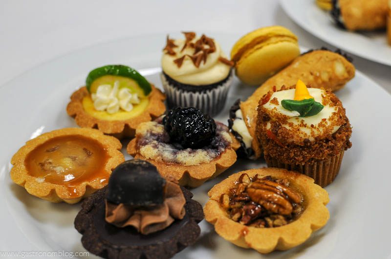A selection of sweets - tarts and macarons and pies from whole foods on a white plate