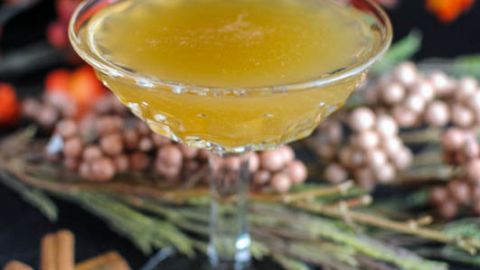 Whiskey Lush Cocktail - gold cocktail in coupe. Cinnamon sticks, flowers in background
