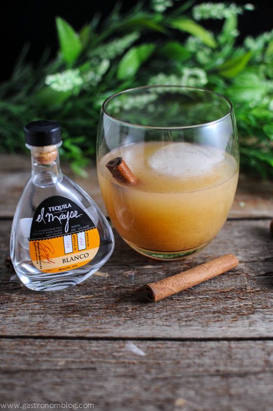 Spiced Pear Tequila cocktail in a glass, with tequila bottle and cinnamon stick