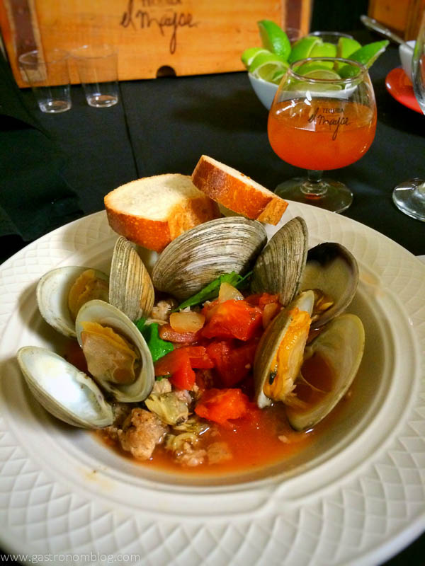Clams in sauce with bread and tequila in glass behind