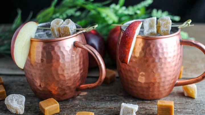 Moscow Mules in copper cups with apple slices and candied ginger. Candied ginger and caramel squares in front