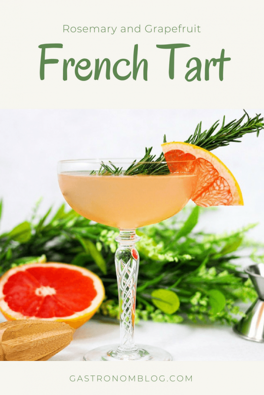 French Tart cocktail in a coupe with grapefruit wedge and rosemary sprig. flowers behind
