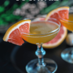 Orange cocktail in coupes, grapefruit slices and purple flowers in background
