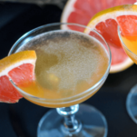 Orange cocktail in coupes with grapefruit slices on black background