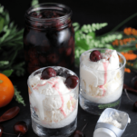 Ice cream in glasses with cherries, ice cream scoop, orange, jar of cherries, flowers