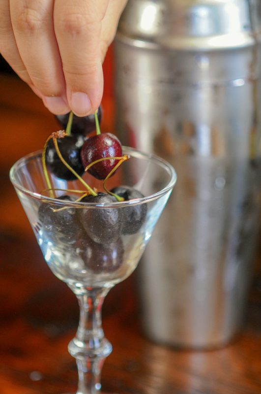 Cherries in a glass, hand picking a few up
