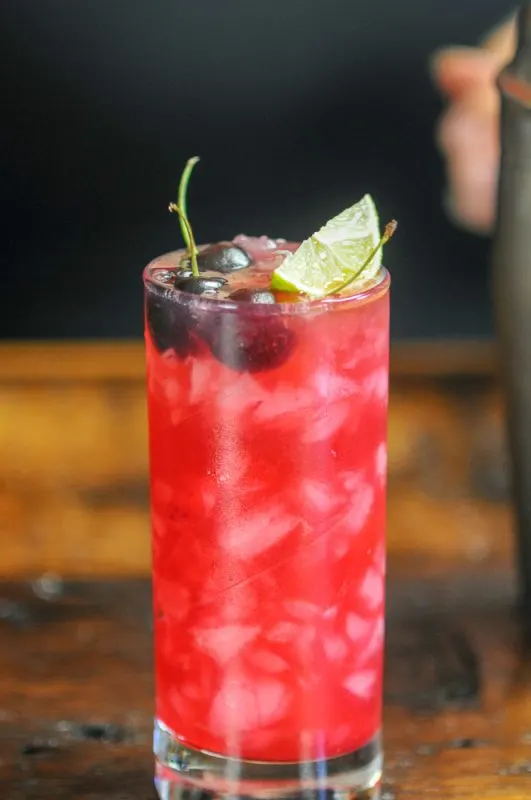 Cherry Cocktail in a highball with a lime and cherries