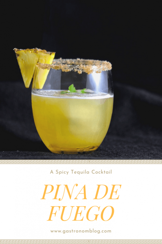 Pina de Feugo Tequila Cocktail, yellow cocktail in front of black background with brown sugar rim and pineapple slice