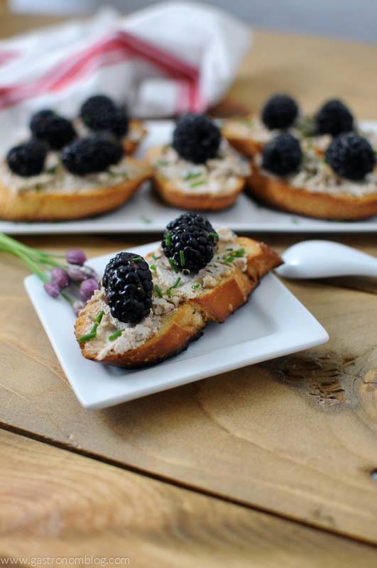 Toasted bread with blackberries on white plates. Napkin in background on wood table