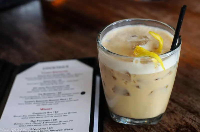 The Beansmith - A coffee and lemoncello cocktail at the Tavern Omaha in a glass with black straw and lemon peel