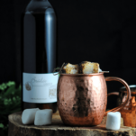 copper mug with cocktail, marshmallows, brulee liqueur bottle behind