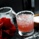 Pink cocktail in glass rimmed with salt, hibiscus flower