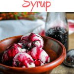 Aronia Berry Simple Syrup - purple syrup on ice cream in wooden bowl. Purple syrup in glass jar behind