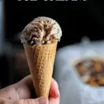 tan ice cream in a cone, hand holding