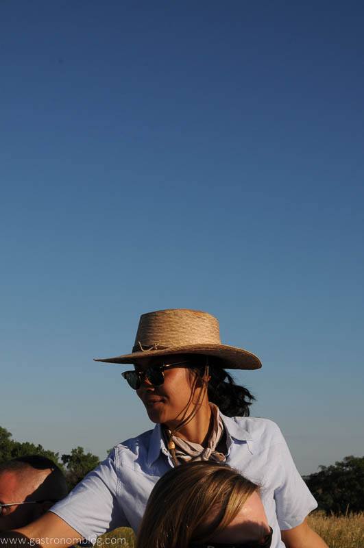 Woman in blue shirt with straw hat serves wine