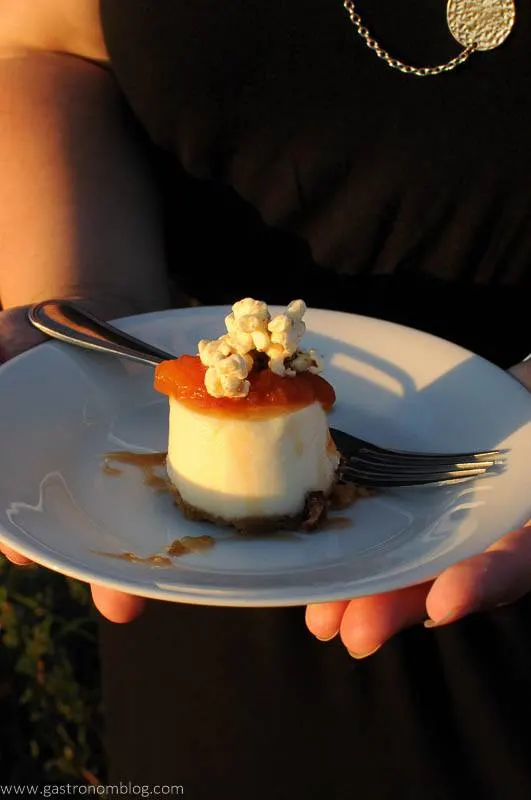 Goat cheese and Caramel tart topped with popcorn o white plate with form, held by hands