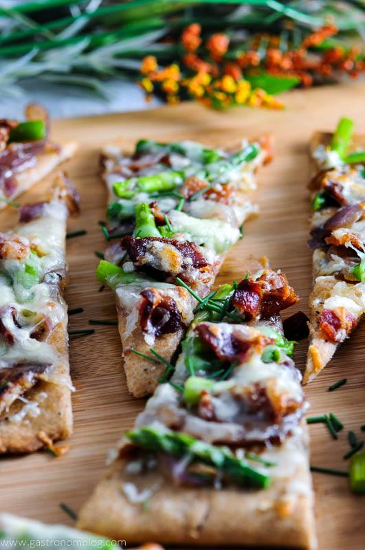 Bacon and Blue Cheese Flat Breads on wood cutting board. White napkin and flowers in background