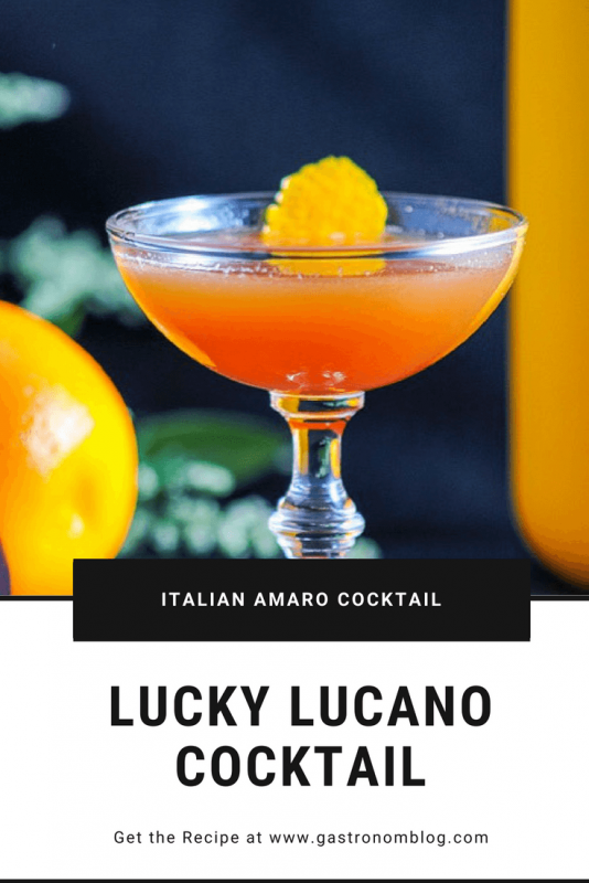 Lucky Lucano Cocktail, orange cocktail in coupe with orange peel. orange and yellow jar behind